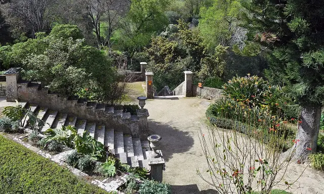 Steintreppen und üppige Vegetation in einem botanischen Garten mit Blick auf Lissabon.