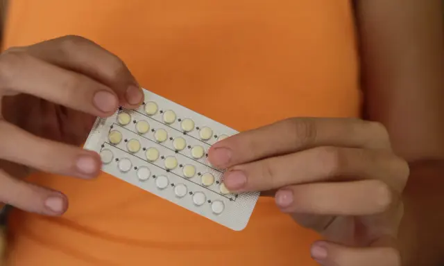 Manos sostienen un blíster de pastillas anticonceptivas. Me he quitado el anillo y no me baja la regla, ¿será por esto?