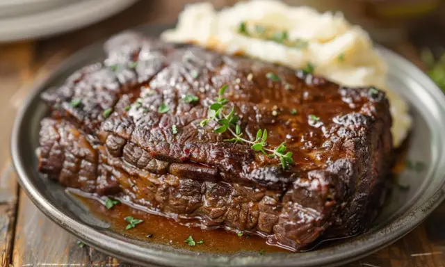 Un plat de jarret de boeuf braisé, tendre et savoureux, servi avec une purée de pommes de terre crémeuse et garni de thym frais.
