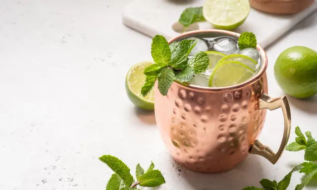 Erfrischender Moscow Mule in Kupferbecher mit Limettenscheiben, Minze und Eis. Perfekt für warme Tage und verschiedene rum sorten.
