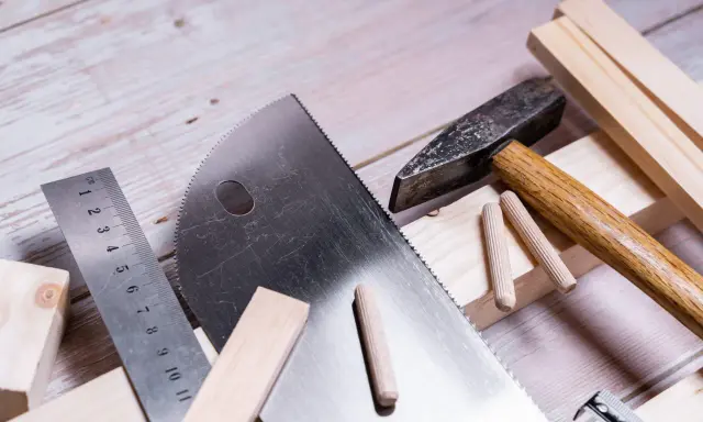 Herramientas para trabajar la madera: sierra, martillo, regla y tacos de madera listos para un proyecto.