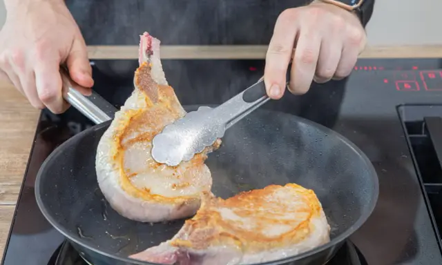 Zwei saftige Koteletts braten in der Pfanne. Perfekt für leckere Kotelett Rezepte.