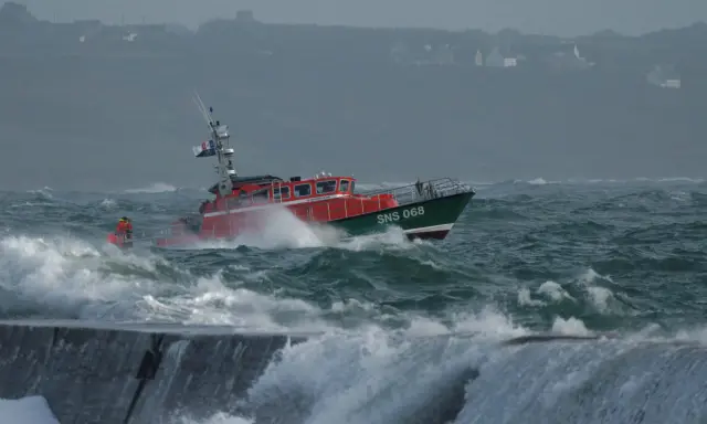 Bateau de sauvetage SNS 068 naviguant dans une mer agitée, affrontant la tempête. Les vagues déferlent sur la proue.