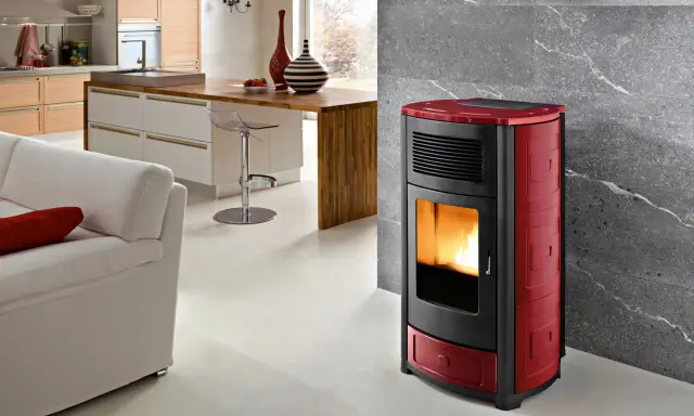 Estufa de pellets roja y negra en un salón moderno, mostrando las ventajas de la biomasa para un hogar cálido y sostenible.