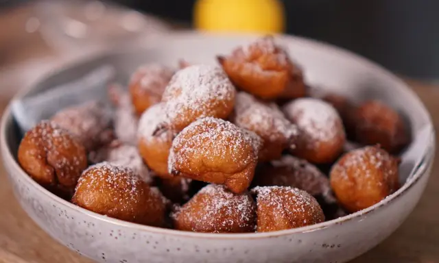 Un bol rempli de beignets dorés, saupoudrés de sucre glace. Parfait pour une recette beignet moelleux rapide.