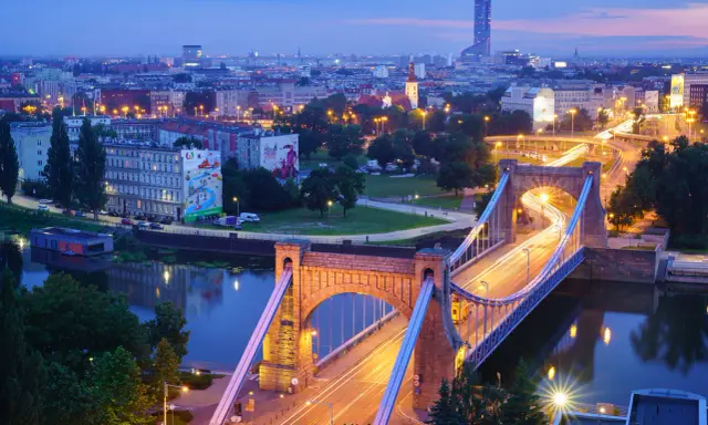 Most Wrocławia w niebieskiej godzinie. Most Grunwaldzki i ruch uliczny tworzą świetlne smugi na tle miasta.