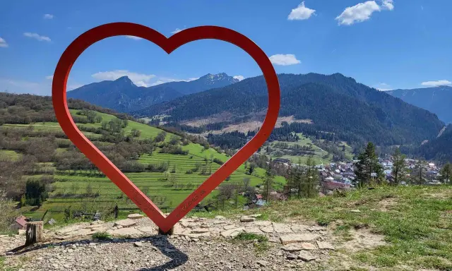 Czerwone serce na tle górskiej panoramy Słowacji. Widok z wieży widokowej na malowniczą dolinę i miasteczko.
