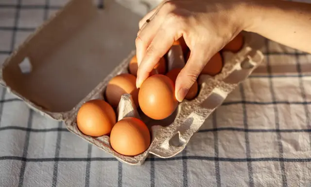 Dłoń wybiera jajko z wytłoczki. Zastanawiasz się, ile kcal ma jajko? To zdrowa przekąska!