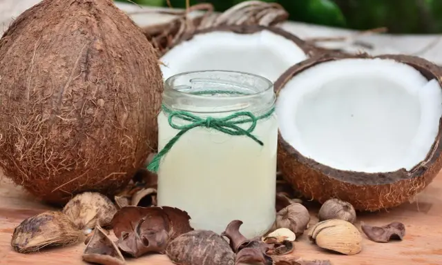Cały kokos, jego połówki i słoiczek z olejem kokosowym. Czy kokos jest zdrowy? Tak, to naturalny produkt.