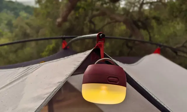 En mysig campingbelysning hänger från tältstången och lyser upp kvällen.