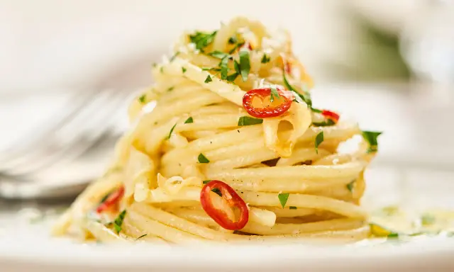 Ein Berg Spaghetti Aglio e Olio, garniert mit frischer Petersilie und scharfen Chilischeiben.