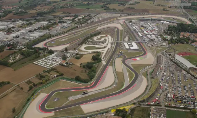 Vista aerea del circuito di Misano, noto anche come circuito San Marino, con tribune piene di spettatori e un vasto parcheggio.