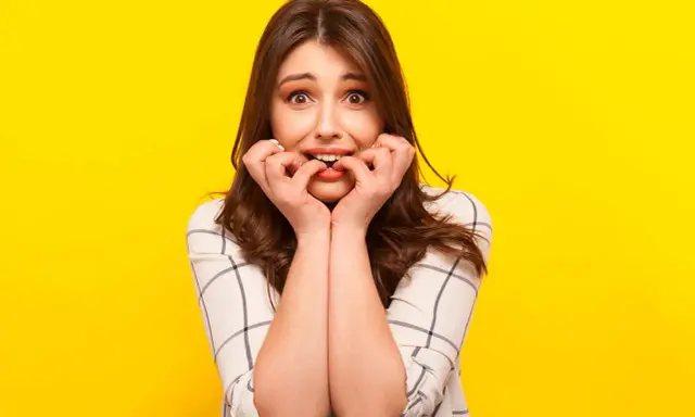 Ragazza con espressione preoccupata che si mangia le unghie, un chiaro segno di gestione dell'ansia.