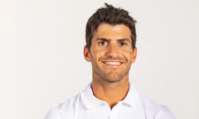 Portrait souriant de Kévin Peponnet, athlète français en polo blanc, sur fond clair.