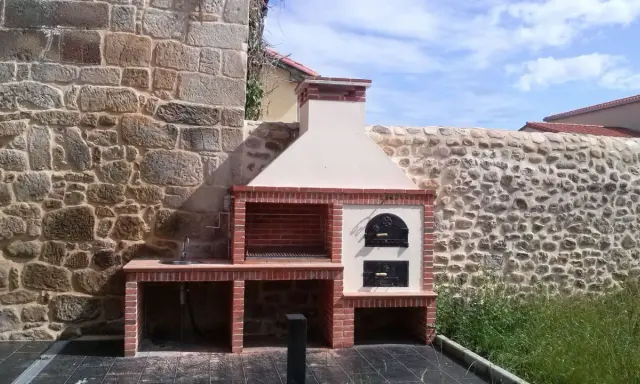 Barbacoa de obra con horno de leña y fregadero, lista para disfrutar de una comida al aire libre.