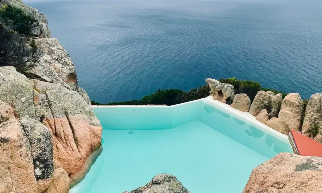 Piscina a sfioro incastonata tra rocce granitiche, con vista sul mare blu intenso. Un angolo di paradiso, forse un progetto di Alberto Ponis.