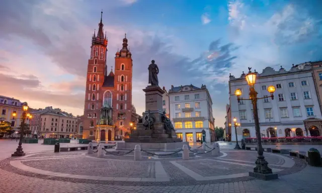 Kraków co warto zobaczyć: Rynek Główny z Kościołem Mariackim i pomnikiem Mickiewicza o zachodzie słońca.