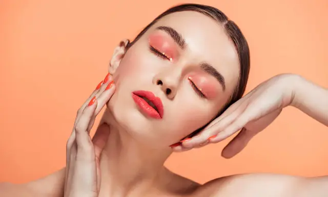 Maquillajes Euphoria: ojos con sombra coral brillante y labios rojos vibrantes, uñas a juego.