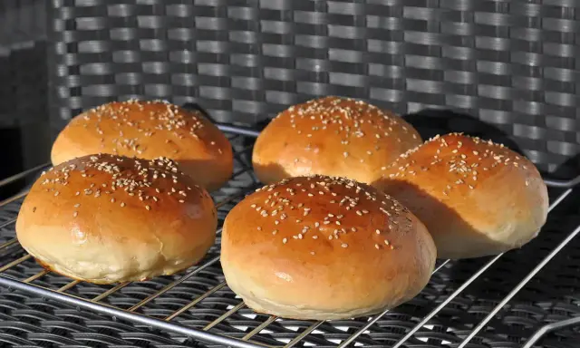 Fünf goldbraune Burgerbrötchen mit Sesam, perfekt für ein Burgerbrötchen-Rezept.