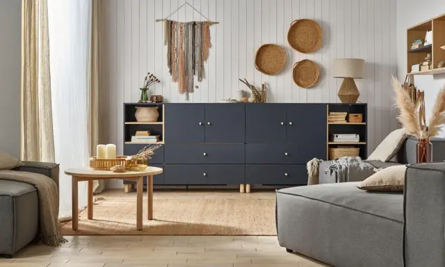 Salon w stylu boho, gdzie beż i granat tworzą przytulną atmosferę. Na ścianie makrama, a na podłodze juta.