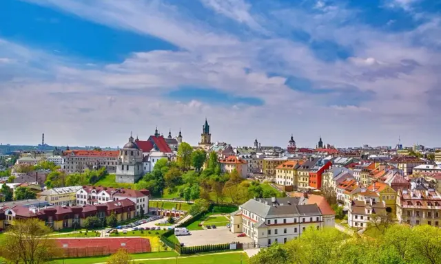 Widok na malownicze miasto w województwie lubelskim. Dachy kamienic, kościoły i zieleń pod błękitnym niebem.