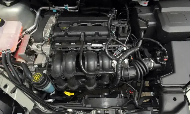 Silnik Ford Focus MK2, widok z góry. Widać kolektor dolotowy, przewody i zbiornik płynu wspomagania.
