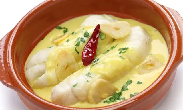Bacalao al pil pil, uno de los platos típicos vascos, servido en cazuela de barro con ajo y guindilla.