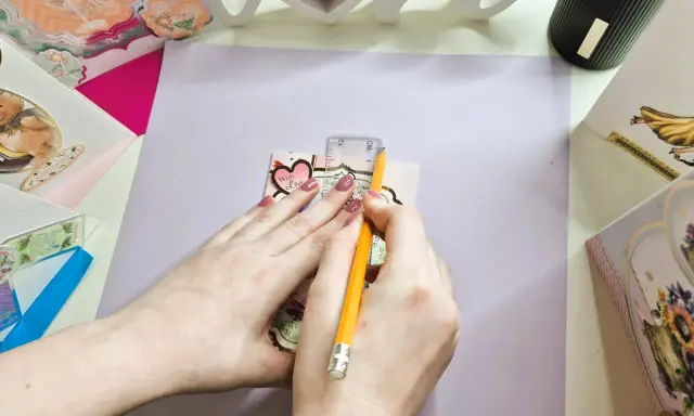 Manos midiendo con regla y lápiz para crear un sobre de papel A4.