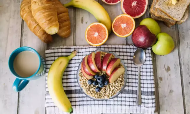 Pyszne i lekkostrawne śniadanie: owsianka z jabłkiem i jagodami, banan, croissanty, cytrusy i kawa.