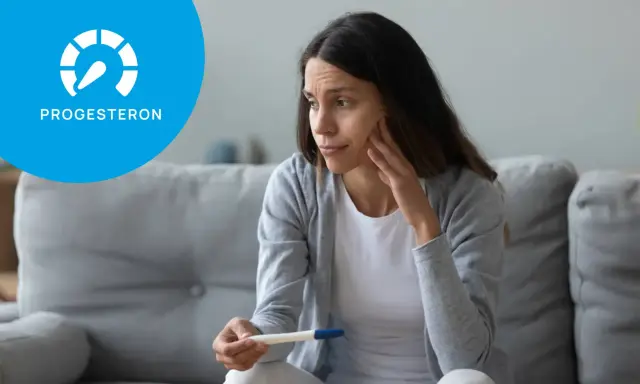 Zmartwiona kobieta trzyma test ciążowy. Ikona progesteronu sugeruje niski progesteron objawy.