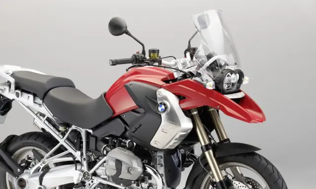 Czerwony motocykl BMW R1200GS z czarnym siedzeniem i dużą szybą.
