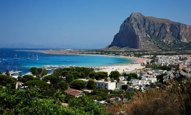 Vista panoramica di San Vito Lo Capo, con la spiaggia affollata e il Monte Monaco. La distanza da Cefalù è di circa 100 km.