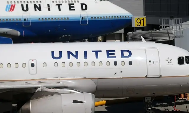 Dwa samoloty United Airlines na płycie lotniska. Jeden z nich to Boeing 747, drugi to mniejszy samolot. W tle widać budynek terminala.