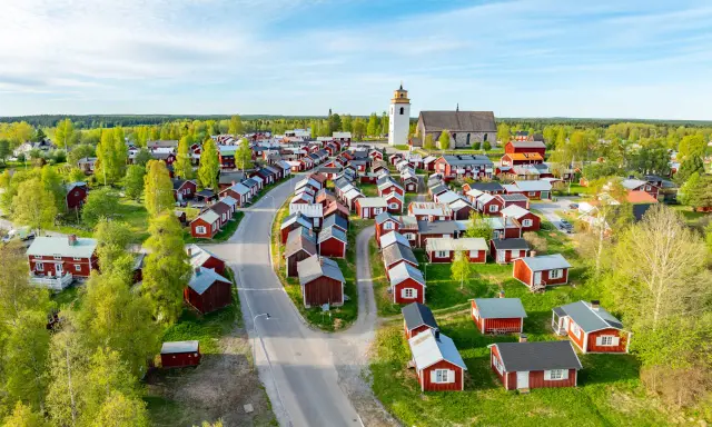 Kyrkstaden Luleå, en idyllisk by med röda hus och en kyrka, badar i solljus.