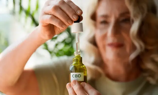 Kobieta trzyma buteleczkę z olejkiem CBD, szukając ukojenia od stresu.