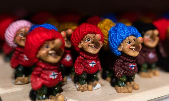 Uśmiechnięte trolle norweskie w kolorowych czapkach i sweterkach z norweską flagą.