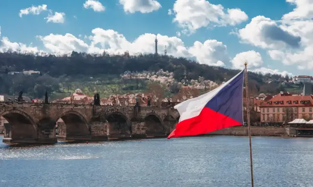 Flaga Czech na tle Mostu Karola w Pradze. Zastanawiasz się, ile idzie paczka z Czech do Polski?