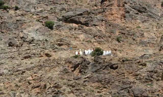 Eine Gruppe von Berber-Algeriern in traditioneller Kleidung wandert auf einem felsigen Hang.