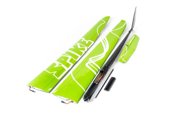 Grüne Flügelteile eines Modellflugzeugs mit weißer Schrift. Ein schwarzer Rumpf mit geöffnetem Batteriefach und 18 AWG Kabeln liegt daneben.