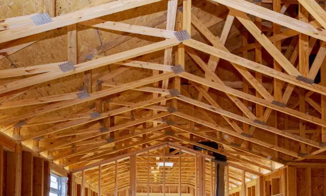 Structure complexe de charpente en bois, avec des fermes et des poutres formant un contreventement bois solide pour une nouvelle construction.