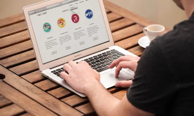 Mężczyzna pracuje na laptopie, przeglądając stronę internetową firmy CyberRabbit. Strona prezentuje usługi: rozwój stron, wsparcie techniczne, grafika i social media. To jest przykład, print co to jest.
