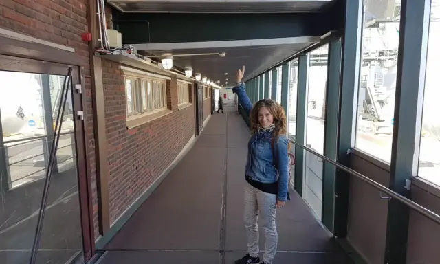 Mujer sonriente saluda bajo el cartel "Welcome to Helsinki". ¡Una aventura en Helsinki con niños comienza!
