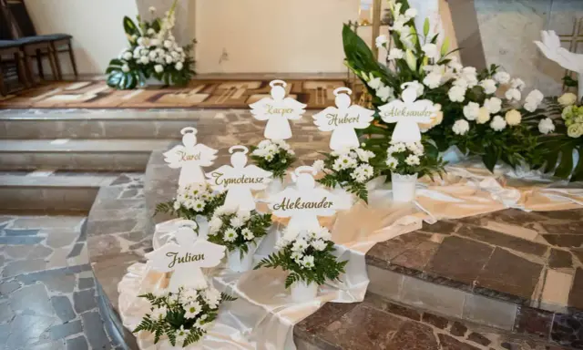 Urocze pomysły na dekoracje komunijne w kościele: aniołki z imionami dzieci i białe kwiaty tworzą niebiańską atmosferę.