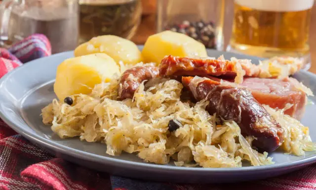 Assiette de choucroute garnie avec pommes de terre, saucisses et lard. Un plat typique de restaurant.
