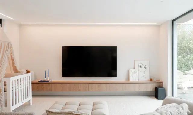 Meuble TV en bois clair, suspendu, offrant une belle profondeur. Une télévision est fixée au mur au-dessus.