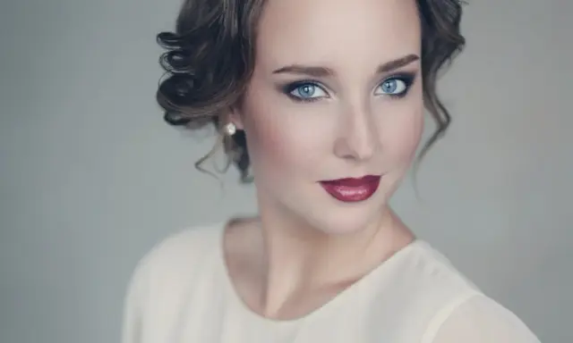 Maquillaje para vestido blanco: ojos ahumados y labios rojos intensos, peinado recogido con rizos.