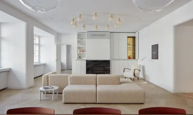 Un moderno sofá en medio del salón, con chimenea y estanterías integradas.