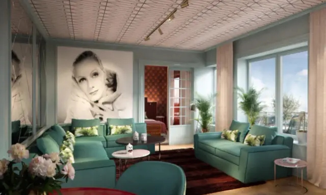 Ett lyxigt vardagsrum med inspiration från art deco i Stockholm. En stor bild av Greta Garbo dominerar väggen, omgiven av turkosa soffor och spegelväggar.