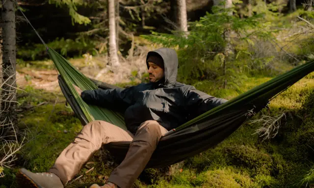 Mężczyzna w hamaku w lesie. To jest właśnie bushcraft – sztuka przetrwania i życia w zgodzie z naturą.