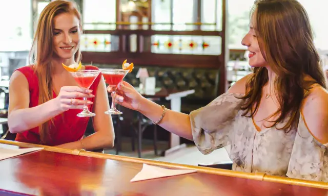 Dwie przyjaciółki wznoszą toast drinkami w barze. Idealny weekend z przyjaciółką!